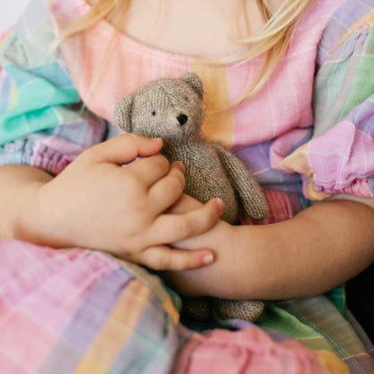 Child holding a teddy bear with colorful bedding in the background