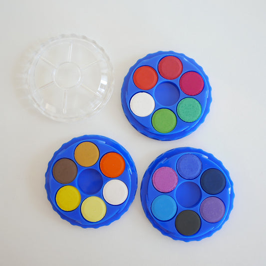Three blue watercolor pans with colorful paint samples on a white background