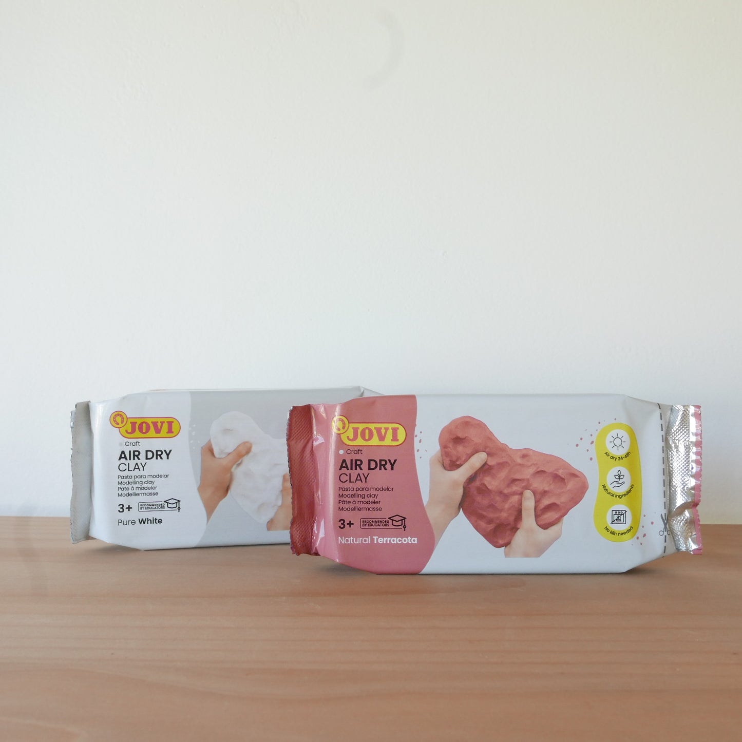 Two packages of JOVI air dry clay on a wooden surface with a white background
