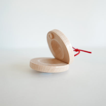 Handmade wooden castanet instrument with smooth natural finish, shown on a white background