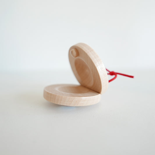 Handmade wooden castanet instrument with smooth natural finish, shown on a white background
