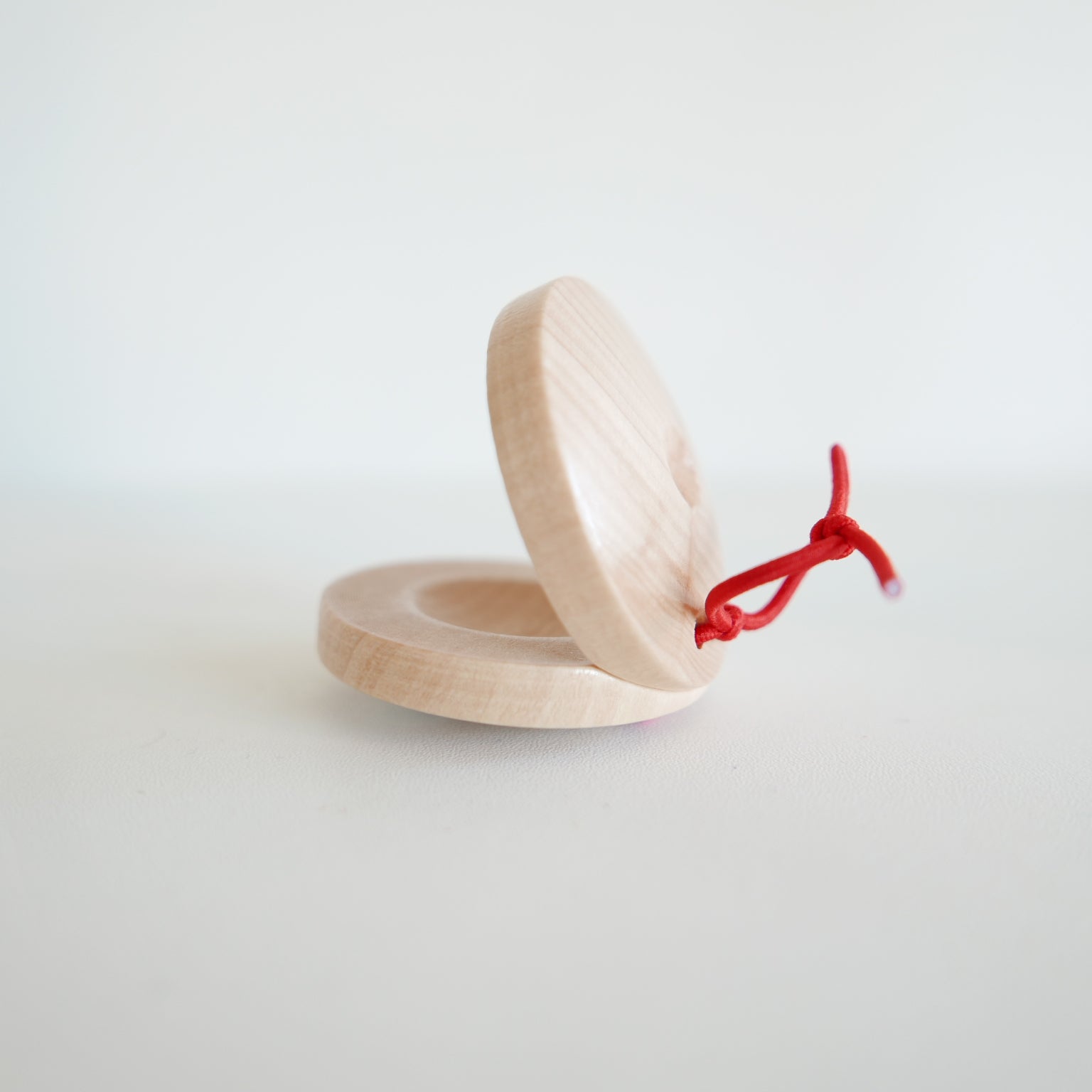 Wooden castanet for rhythm and music play, featuring round shape and simple design, photographed against white