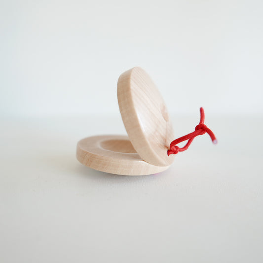 Wooden castanet for rhythm and music play, featuring round shape and simple design, photographed against white