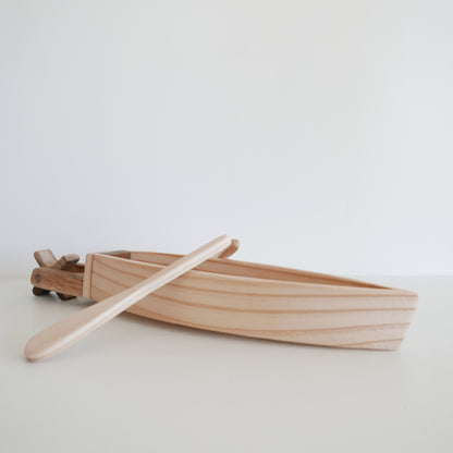 Wooden toy boat with oar on a white background
