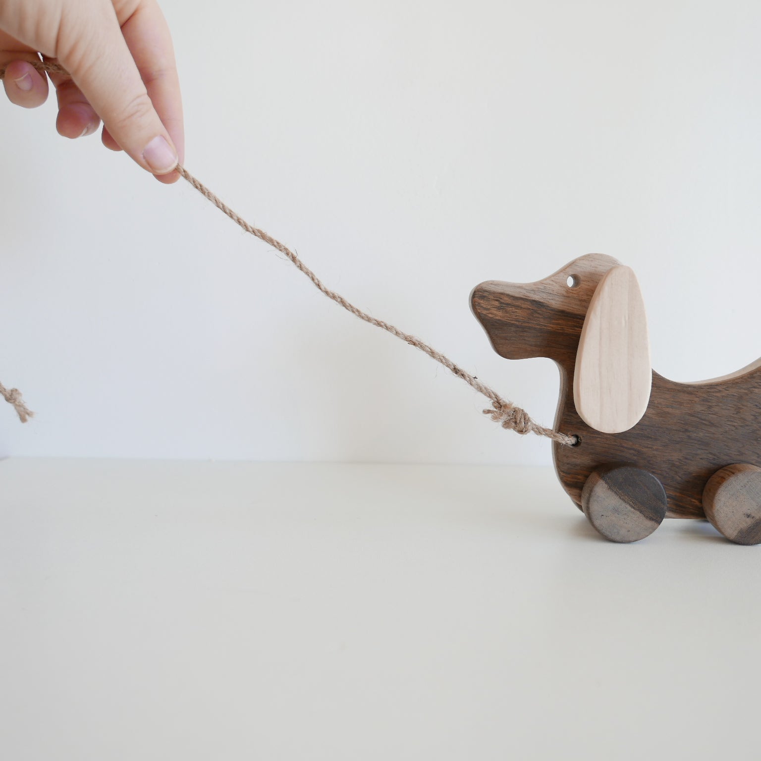 Wooden dog pull toy with a hand pulling on a string 
