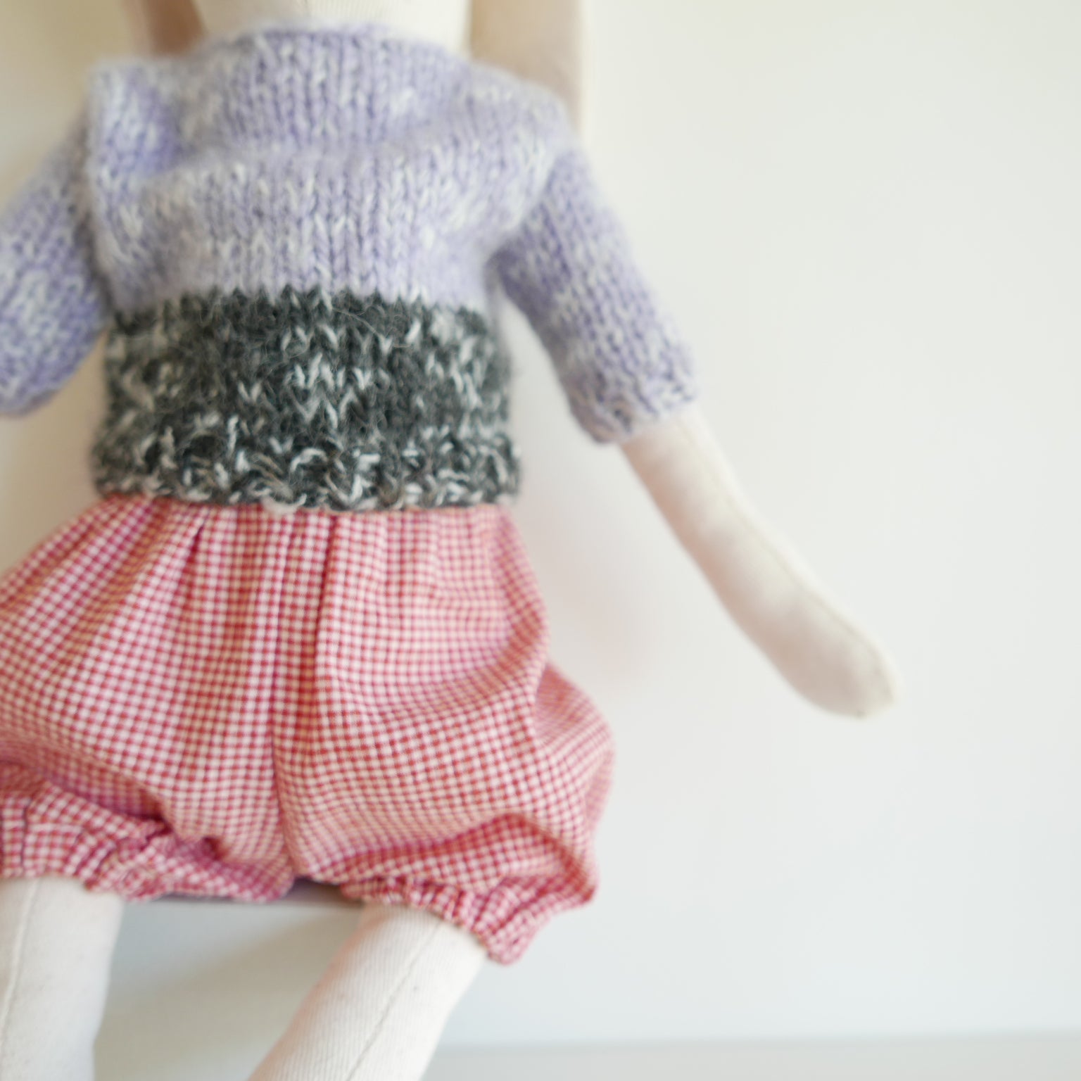 Knitted sweater and red checkered shorts on a mannequin against a white background