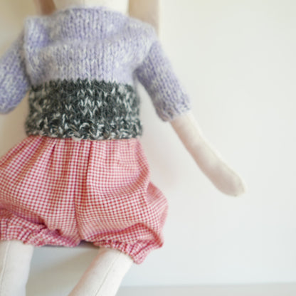 Knitted sweater and red checkered shorts on a mannequin against a white background