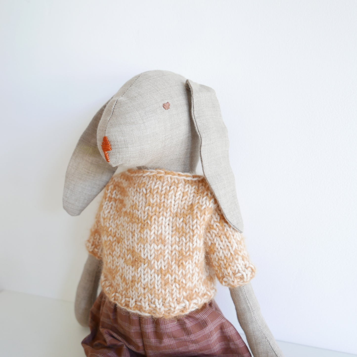 Toy rabbit wearing a knitted sweater on a white background