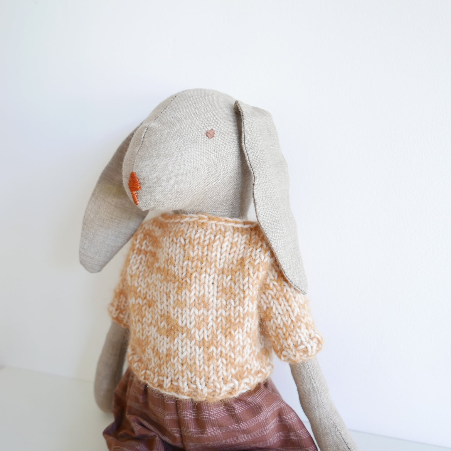 Toy rabbit wearing a knitted sweater on a white background