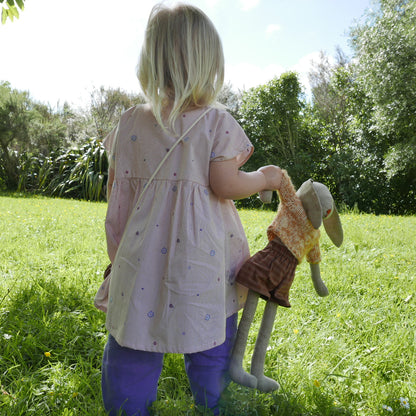 Child holding a stuffed animal in a grassy outdoor setting